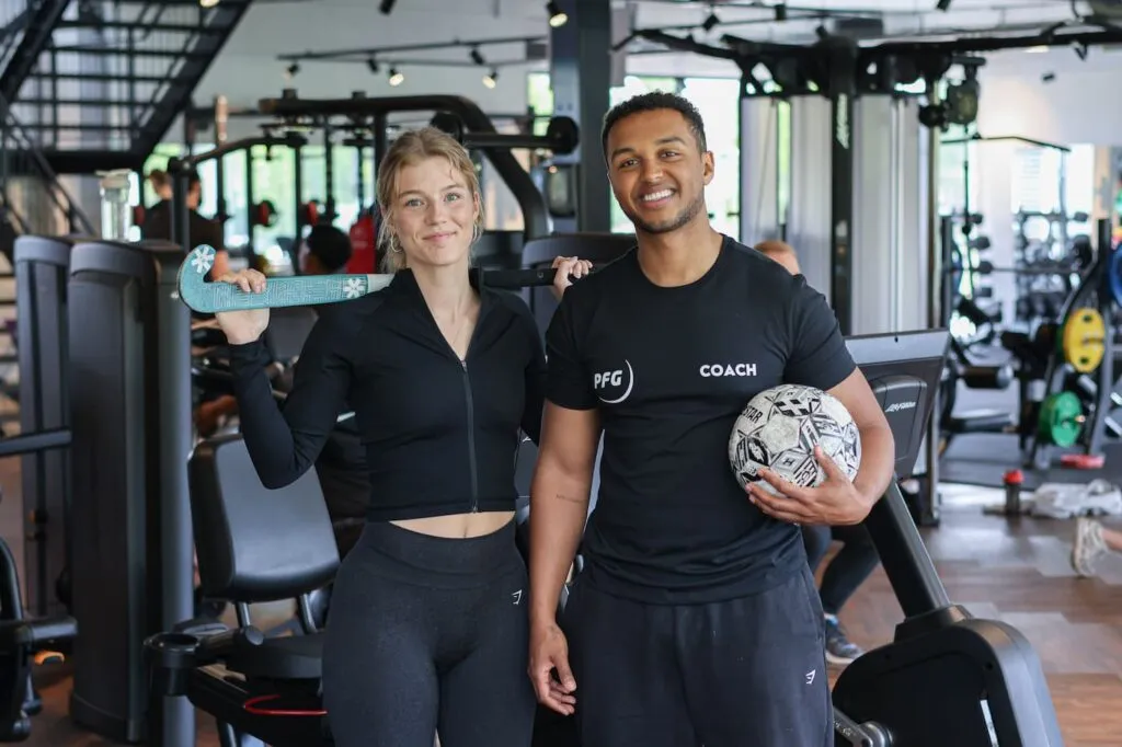ProFit Gym Coach En Vrouwelijke Sporter Met Hockeystick En Voetbal